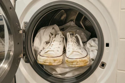 Baskets Converse blanches placées dans un tambour de machine à laver avec un filet de protection pour un lavage délicat