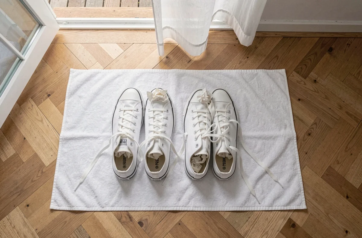 Paire de Converse blanches propres posées sur une serviette pour sécher à l'air libre après un lavage en machine